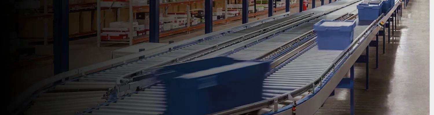 Conveyor system moving cartons and totes between work zones to automate material flow across a warehouse