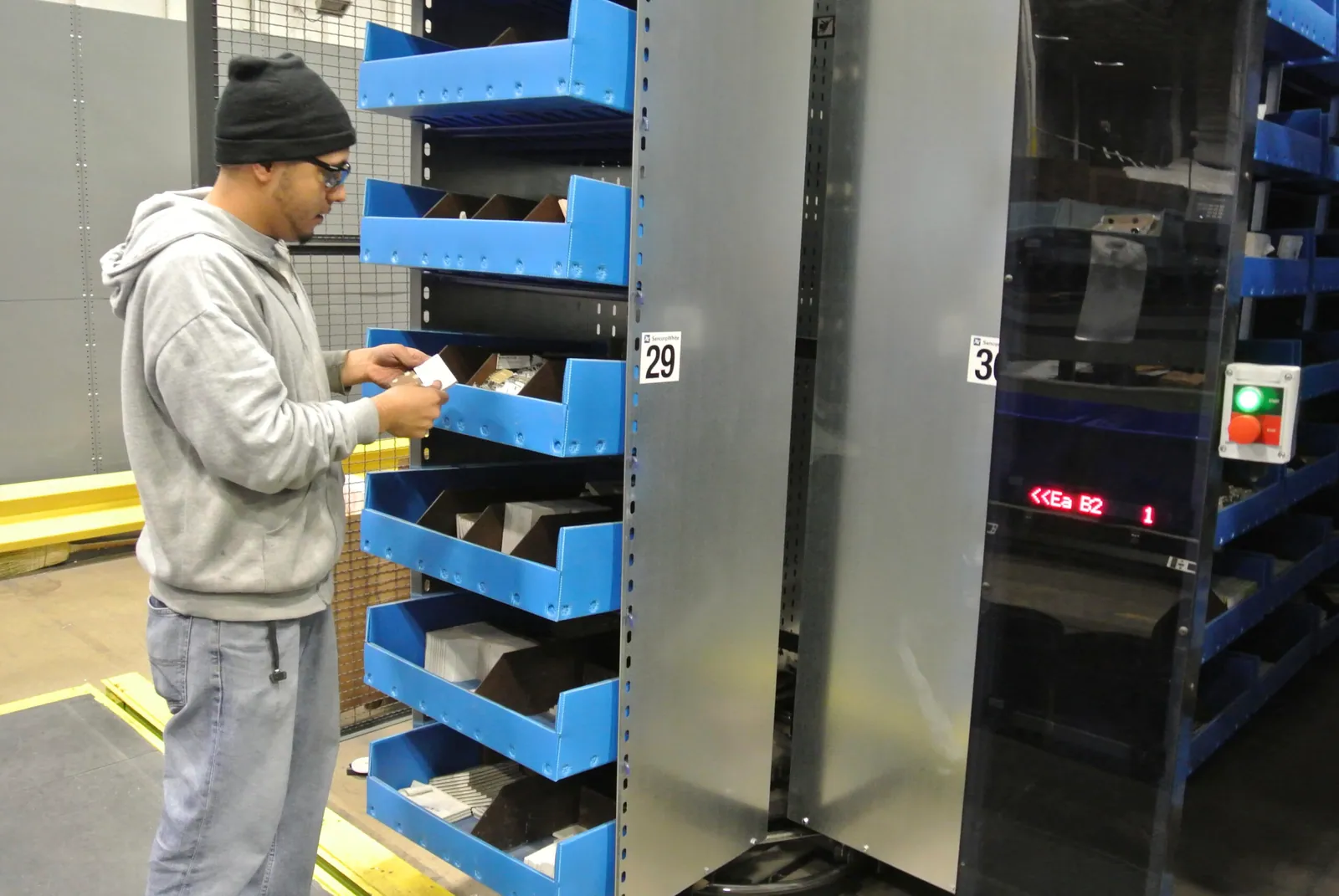 Warehouse operator picking individual items from blue bin shelving in a broken case fulfillment operation