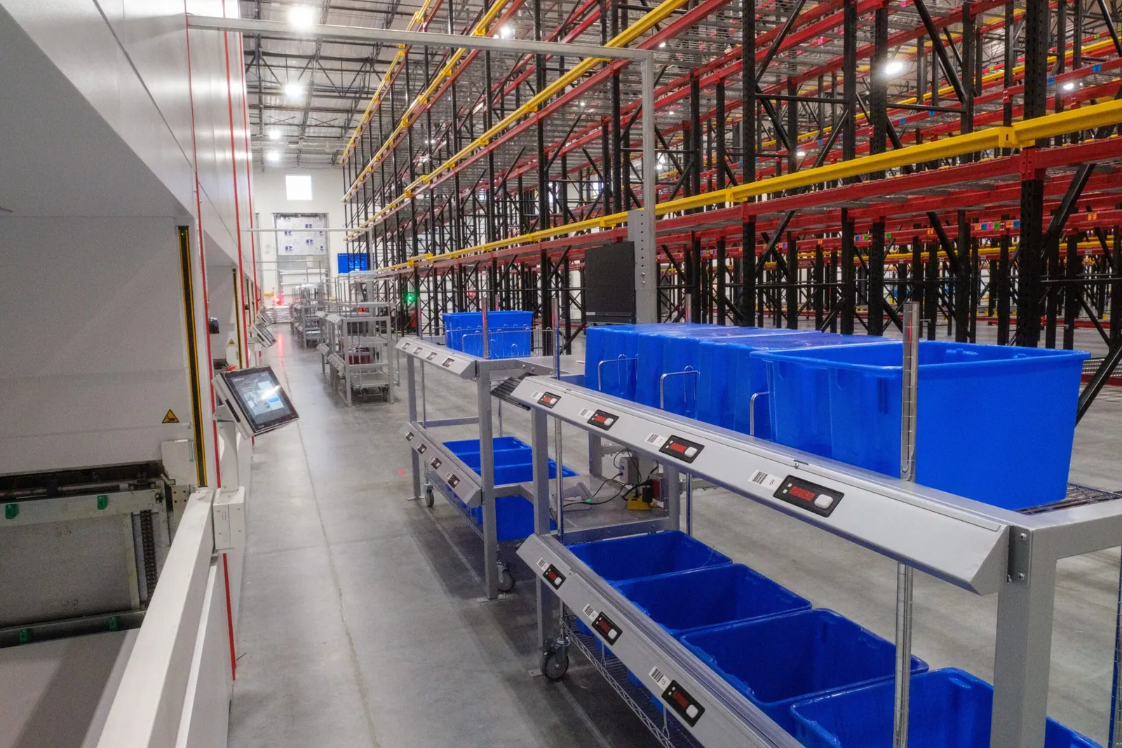Warehouse pick-to-light shelving aisle with illuminated location displays guiding an operator to the correct bin